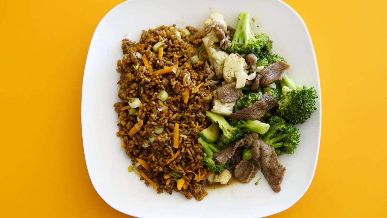 A high angle shot of delicious fried rice with beef and veggies isolated on a yellow background