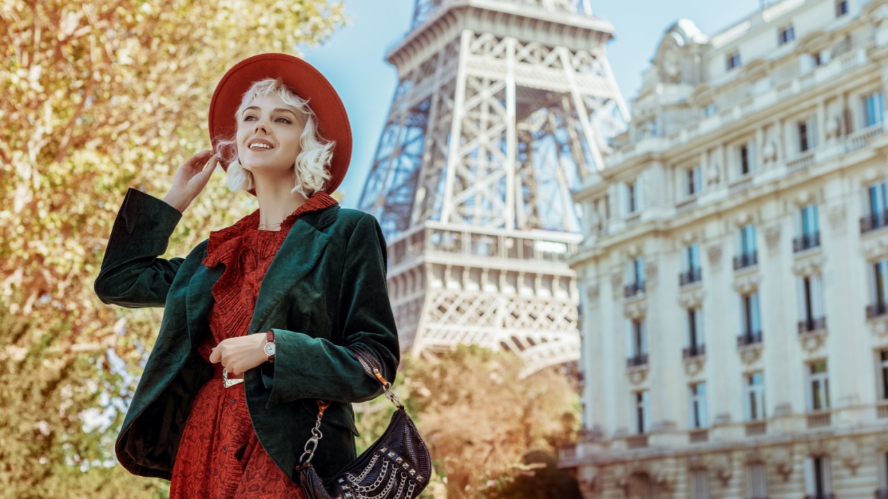Happy, smiling fashionable woman wearing stylish autumn outfit: orange hat, dress, green velvet blazer, holding purple leather handbag, posing in street of Paris. Copy, empty space for text