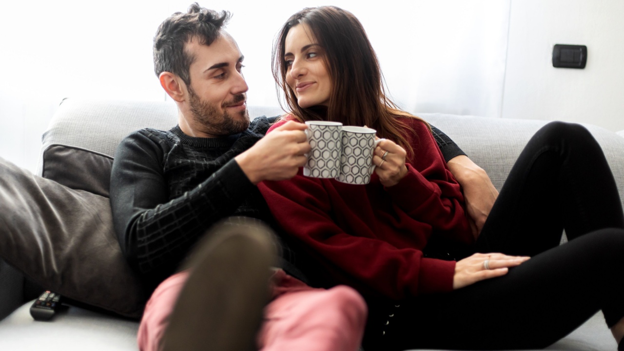 Couple toasting coffee mugs on a sofa