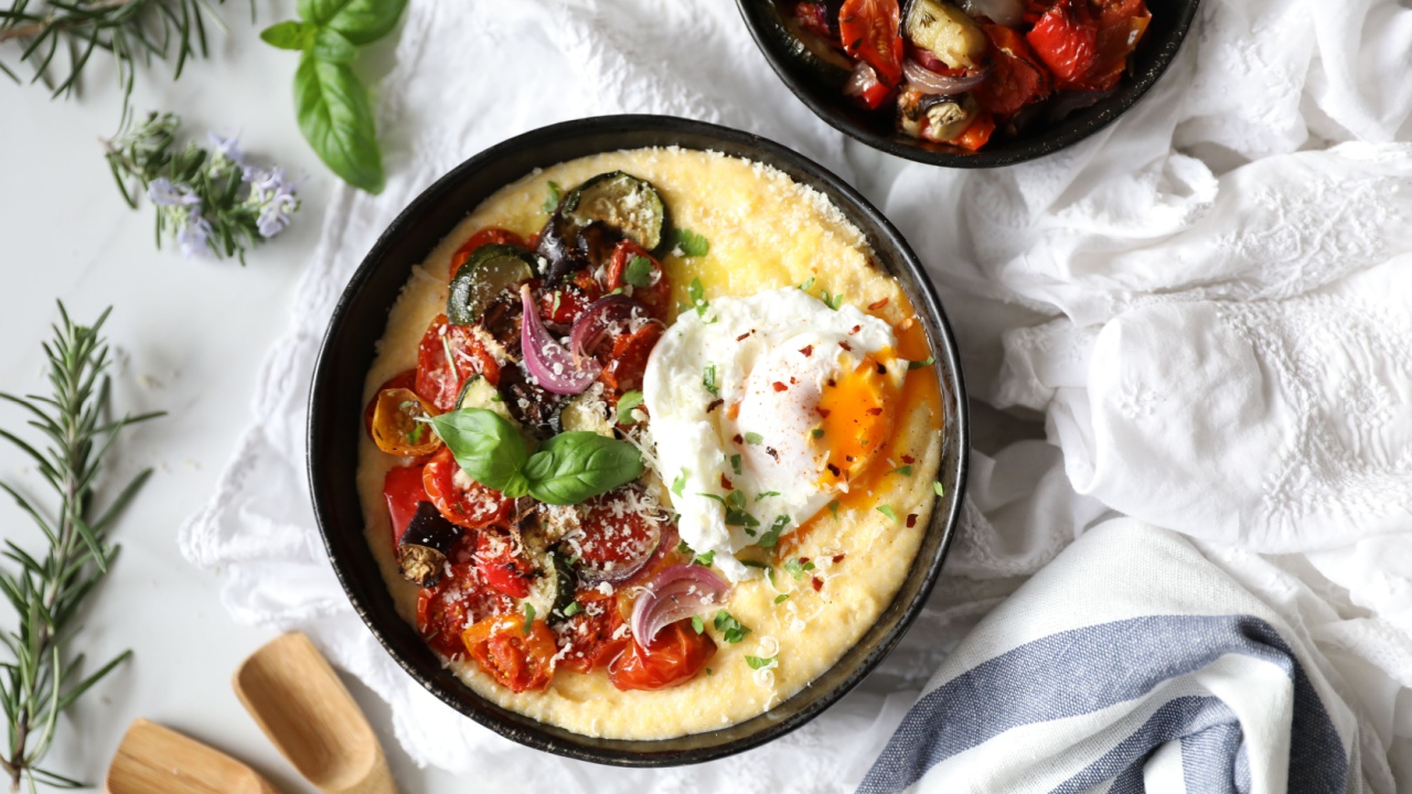Creamy Parmesan Polenta with roasted vegetables, poached egg garnished with basil leaves and fresh herbs. White background copy space, flat lay. Balanced vegetarian meal, Italian cuisine concept