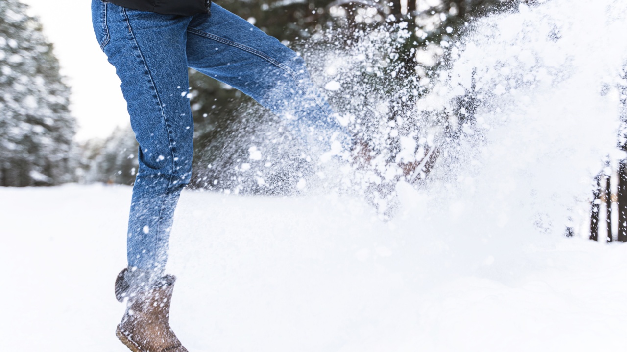 Winter outdoor fun. Woman wearing sheepskin boots is kicking snow.