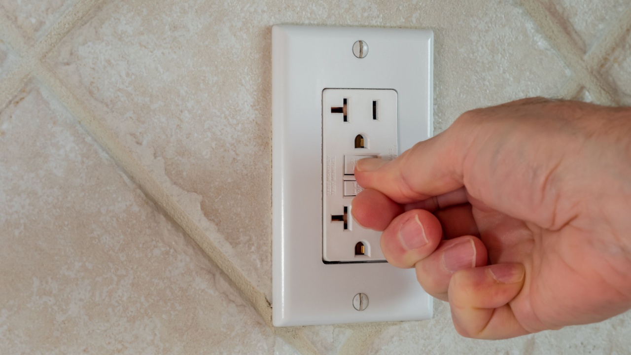 Resetting GFCI ground fault interrupter electricity receptacle and wall plate. Residential electric plug with GFI reset button.