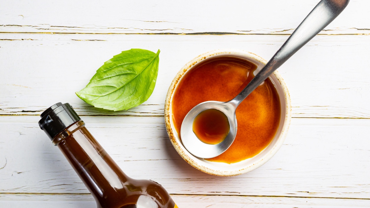 Worcestershire sauce in a bowl with spoon and bottle over white background, top view