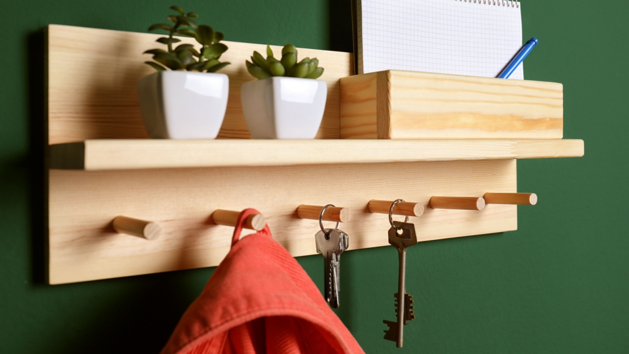 Wooden hanger for keys with clothes on green wall, closeup