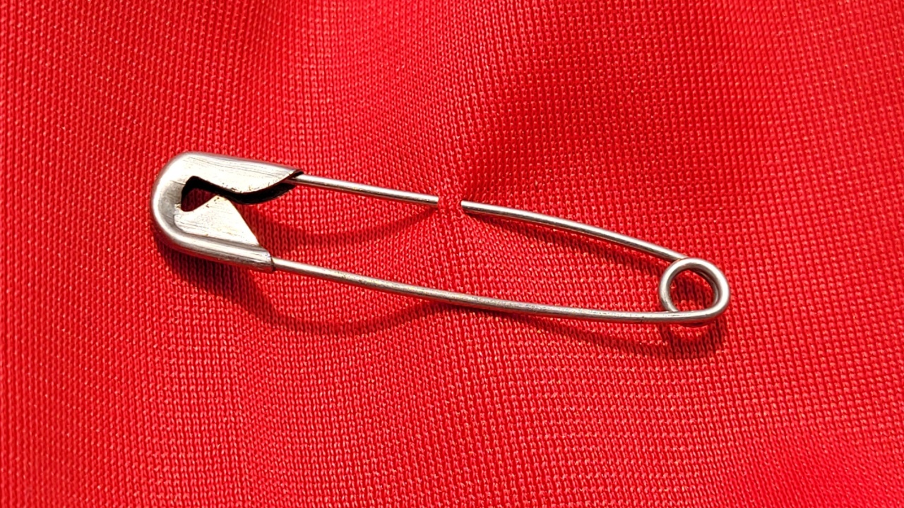 Safety pin attached to red shirt background