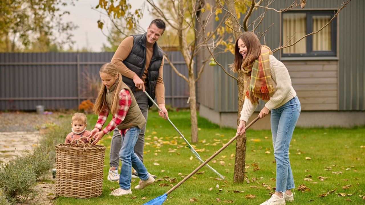 Man and woman raking leaves children near basket