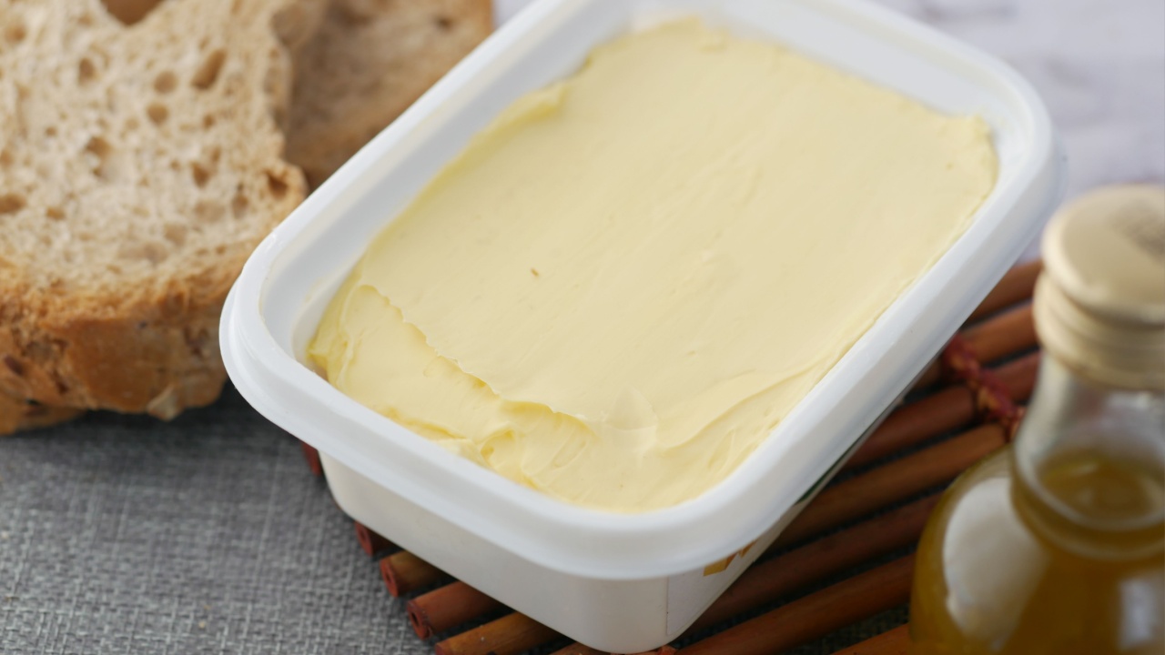 fresh butter in a container with bread on white background