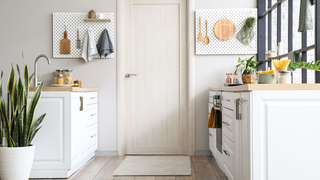 Interior of modern kitchen with white counters, door and peg boards