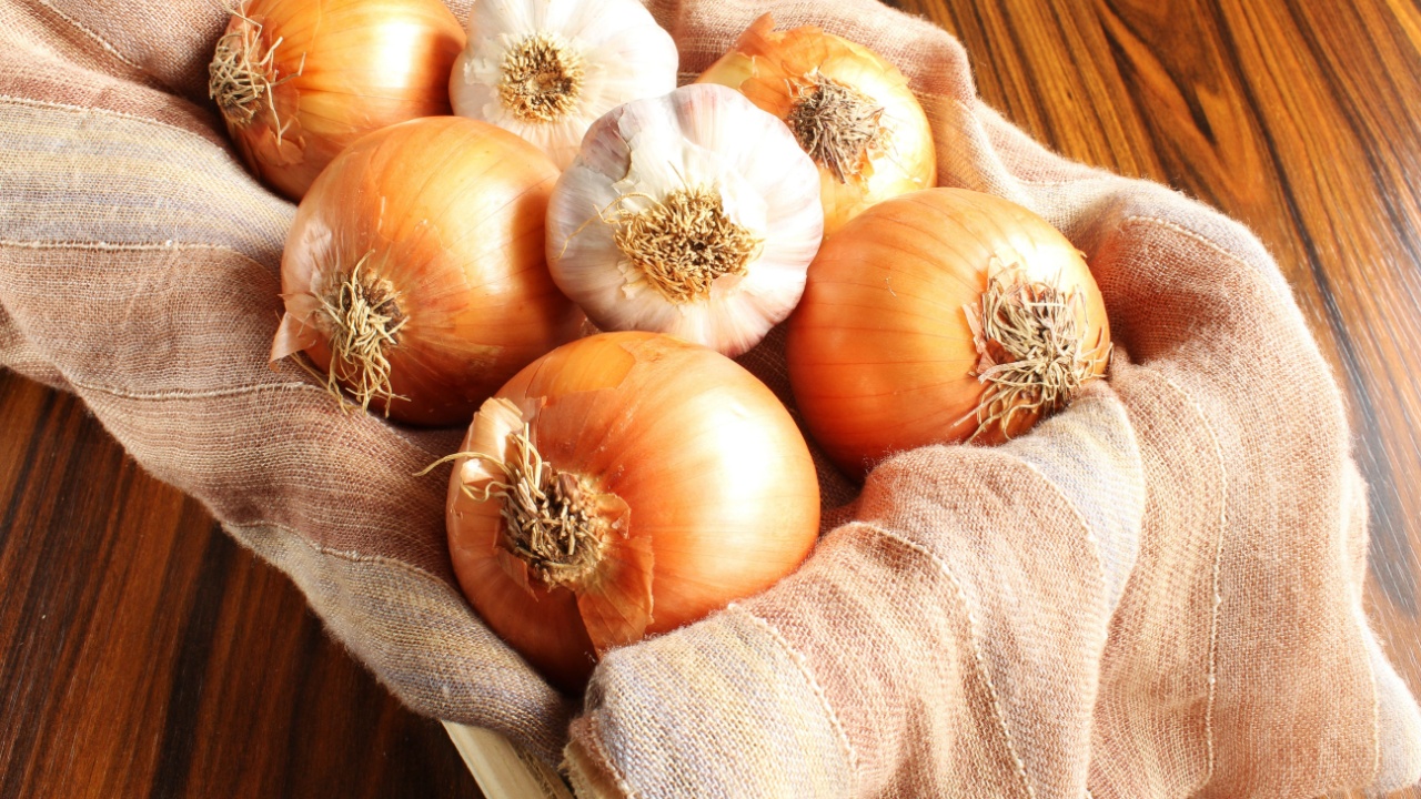 Onions and garlics. Garlic bulbs and onions in the wooden box.