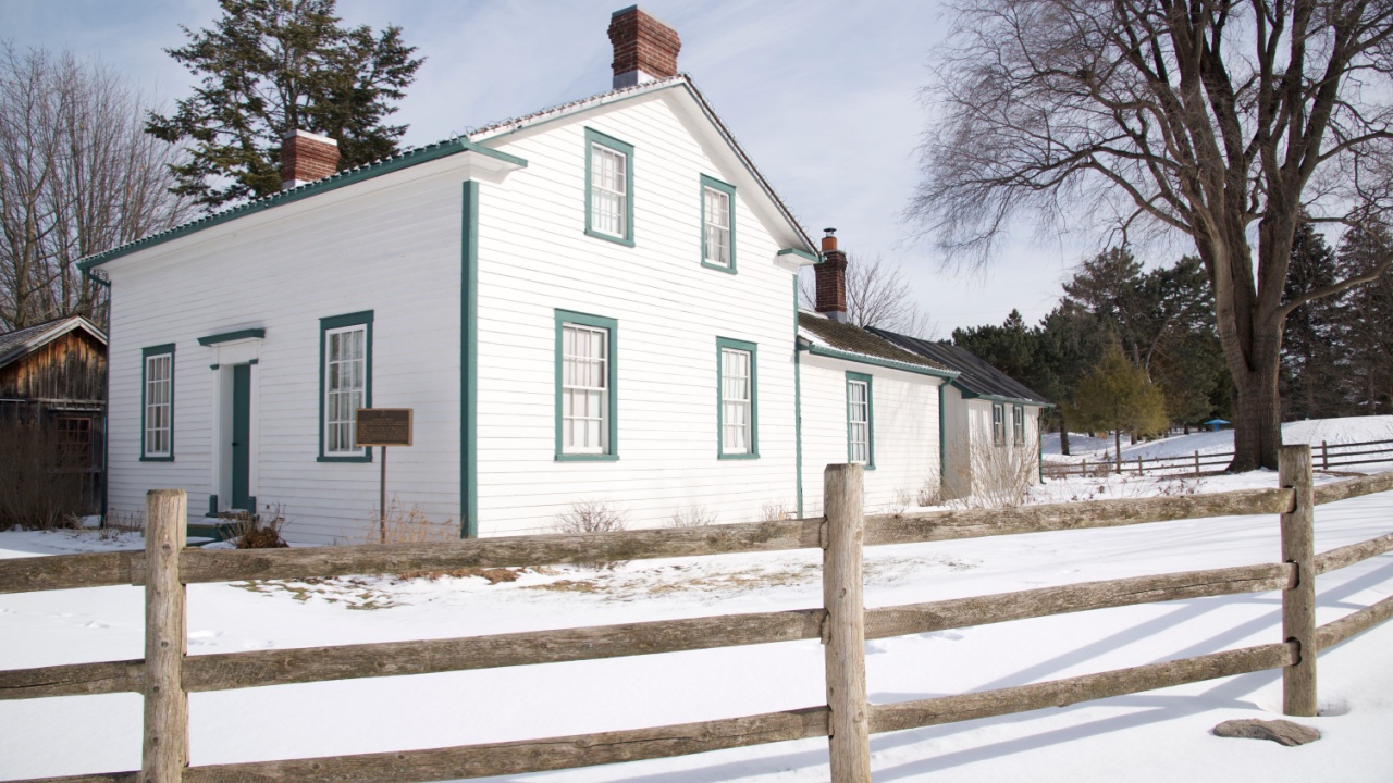 Victorian-style house exterior with wooden post and rail fence in winter. 