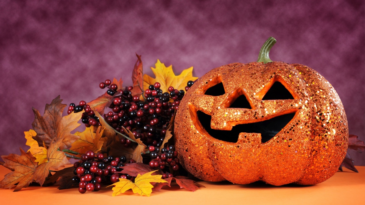 Happy Halloween orange glitter jack-o-lantern pumpkin with autumn leaves and berries against a bright modern colorful dark pink and orange background.