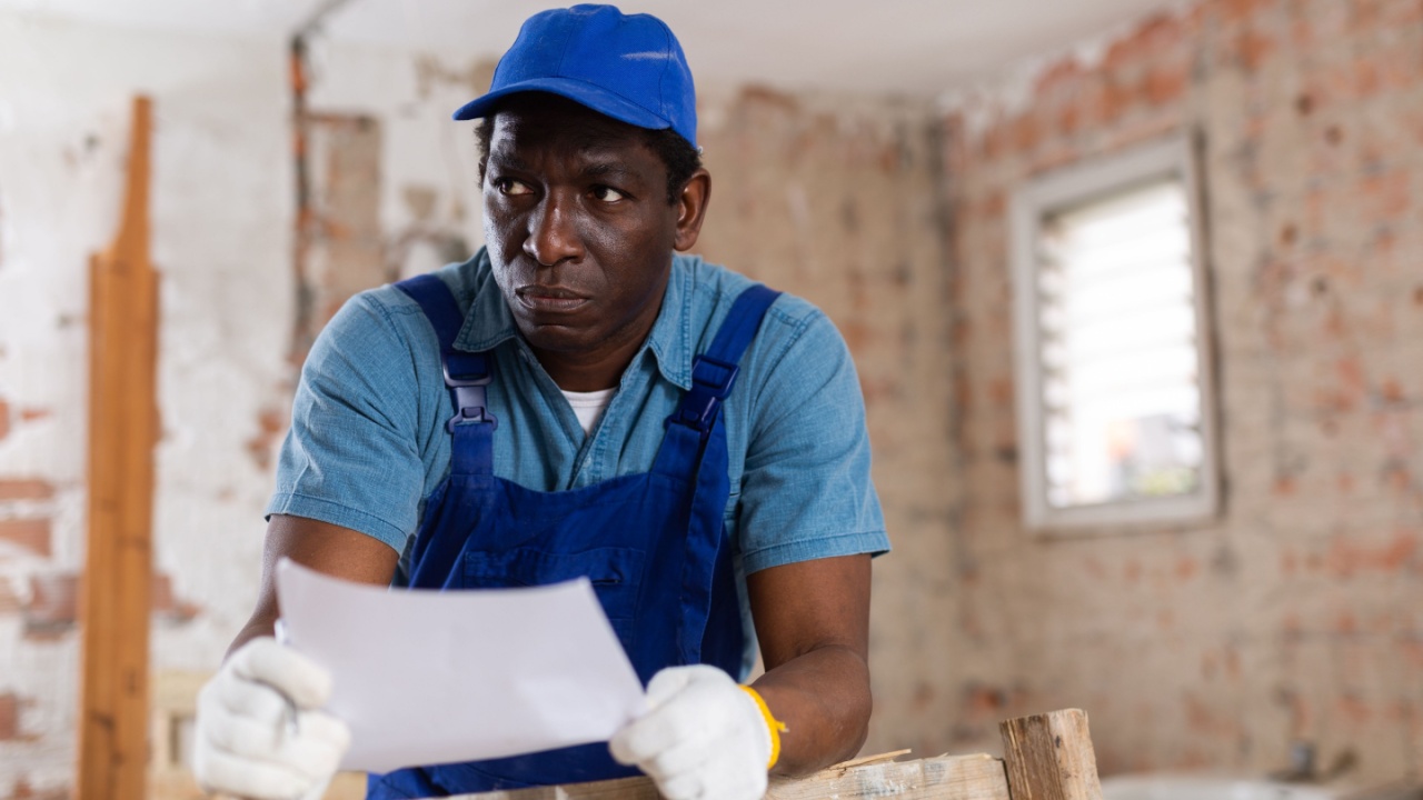 Upset adult african american contractor having problem with with building permits, standing at construction site indoors, looking through papers