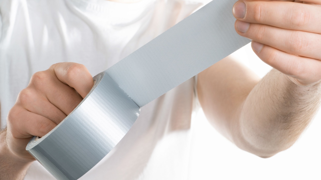 Close up image of man holding adhesive duct tape white background. male hands trying to fix something.