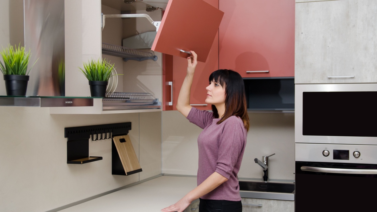 A young woman opens a lift-up wall cabinet door in the kitchen