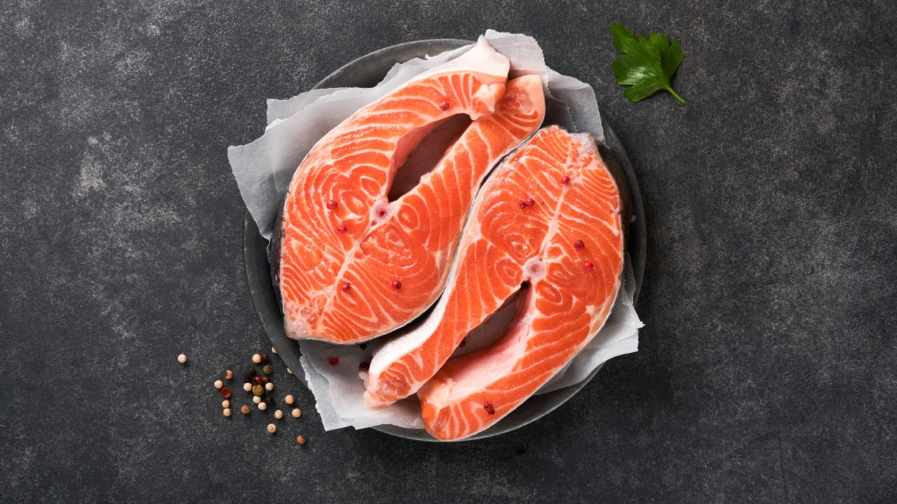 Salmon. Raw salmon steak. Fresh raw salmon fish with cooking ingredients, herbs and lemon prepared for grilled baking on black background. Healthy food. Top view. Copy space.