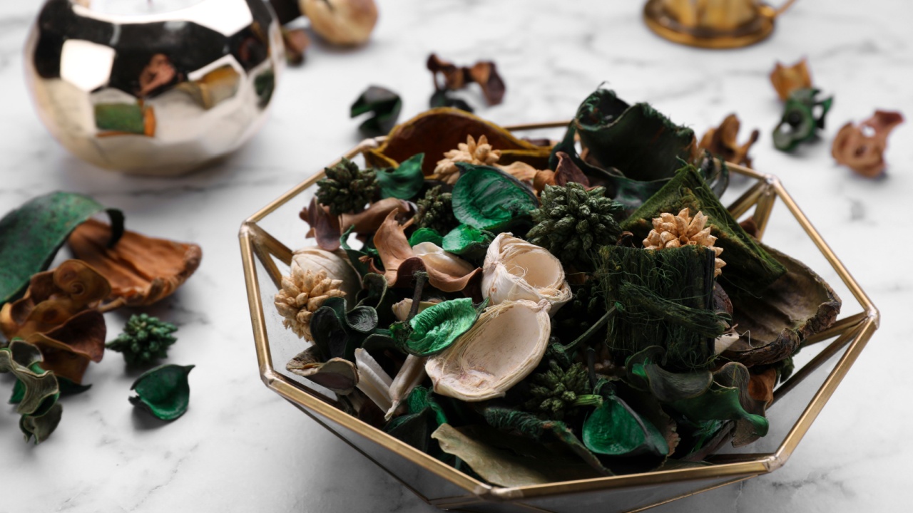 Aromatic potpourri of dried flowers in bowl on white marble table, closeup
