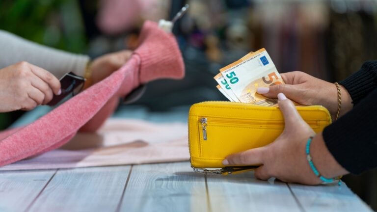 Counter with a customer paying in cash taking out euro bills from her wallet