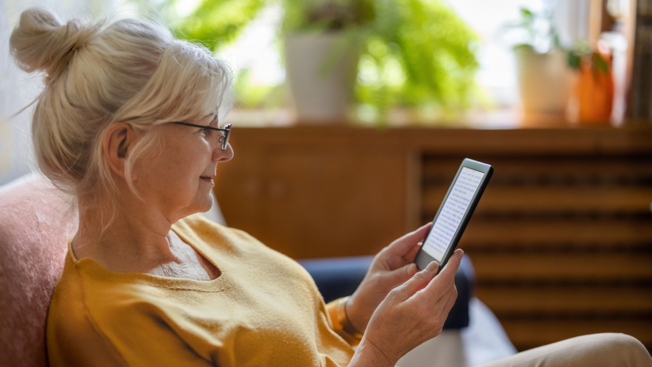 Senior woman using e-reader and reading an e-book at home
