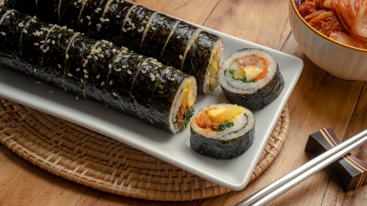 Korean Sushi Rolls or Kimbap is a popular Korean dish in white plate on wooden table, California Maki, Steamed rice wrapped in seaweed with shrimp eggs meat and vegetable.