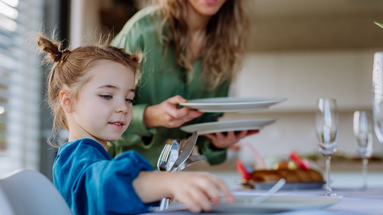 Close-up of mother with her daughter setting table, celebrating Easter.