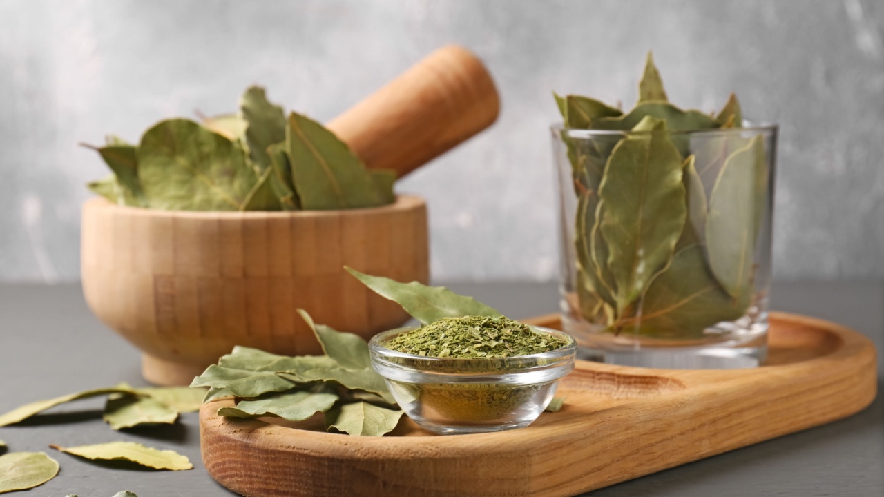 Whole and ground dry bay leaves on grey table, closeup