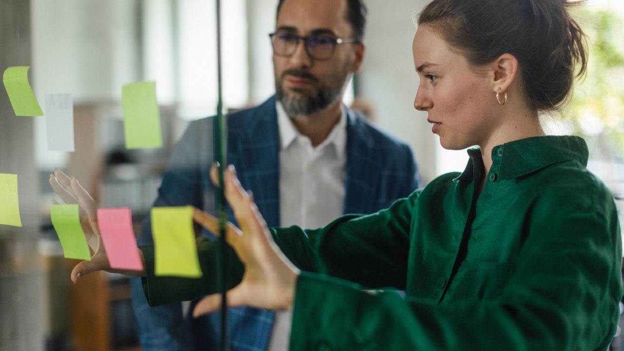 Young woman showing notes in office to her colleague.
