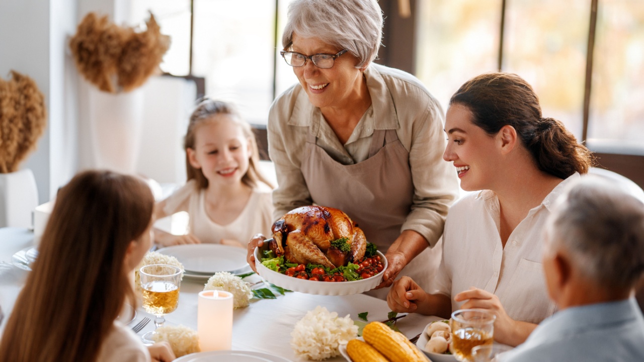 Thanksgiving Day, Autumn feast. Happy family sitting at the table and celebrating holiday. Grandparents, mother and children. Traditional dinner.