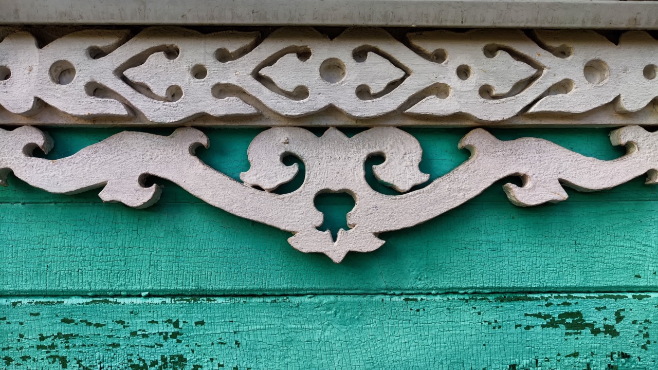fragment of wooden carved patterns on black background. Windows of wooden house are decorated with carvings, platbands, wooden lace ornaments. Russian traditional wooden architecture