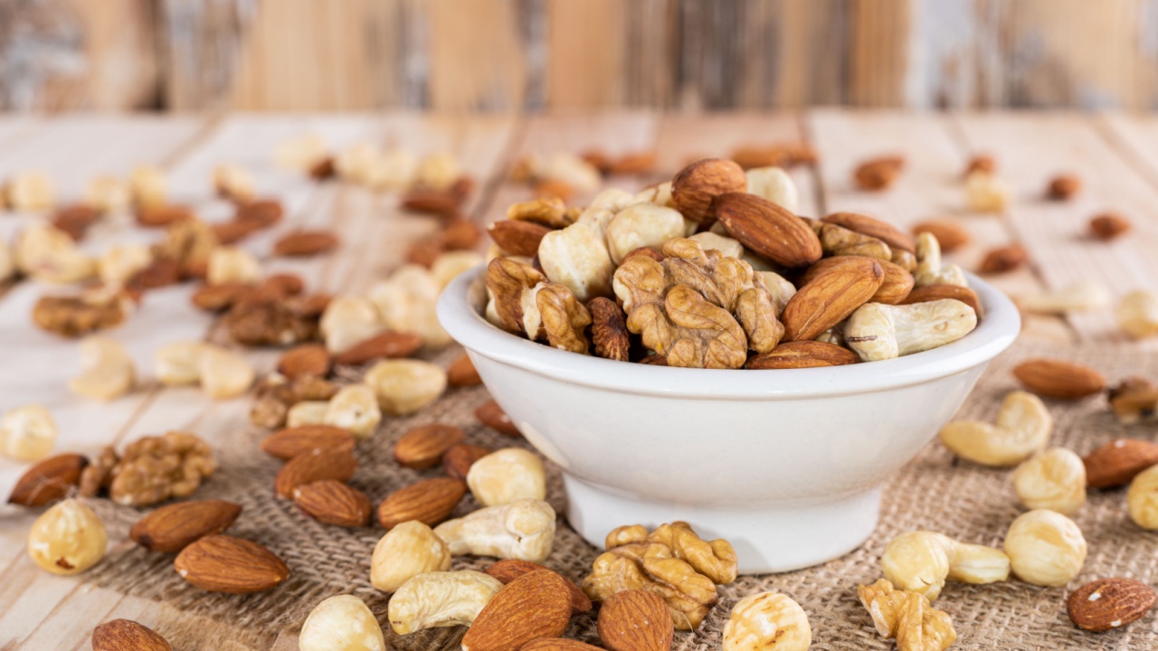 Assorted nuts - almonds, cashews, hazelnuts or filberts, walnuts, in white bowl on wooden background.