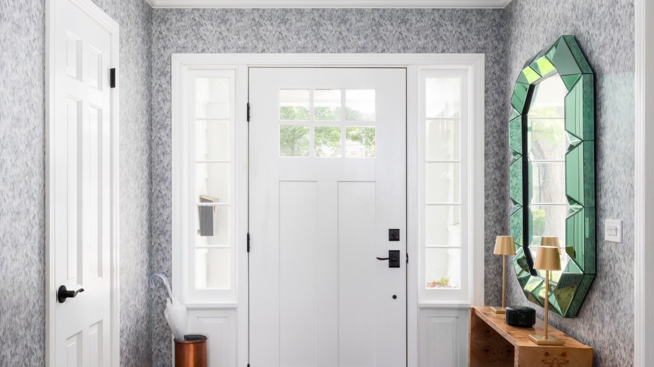 An entryway mudroom detail with wallpaper, a purple ceiling and gold light fixture, and a white doorway and windows.