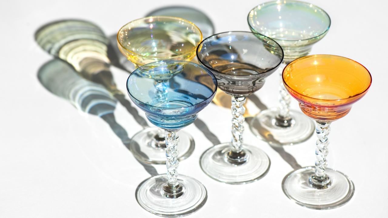 Crystal colorful stemware set with reflection over white background. Colourful elite set of empty alcohol liquor glasses on white, border design. Stemmed glasses, drinkware closeup