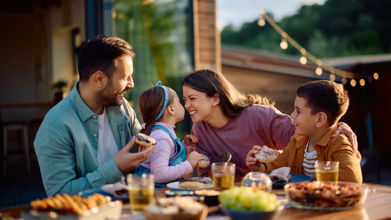 Happy family having fun while eating at dining table on a patio in spring day.