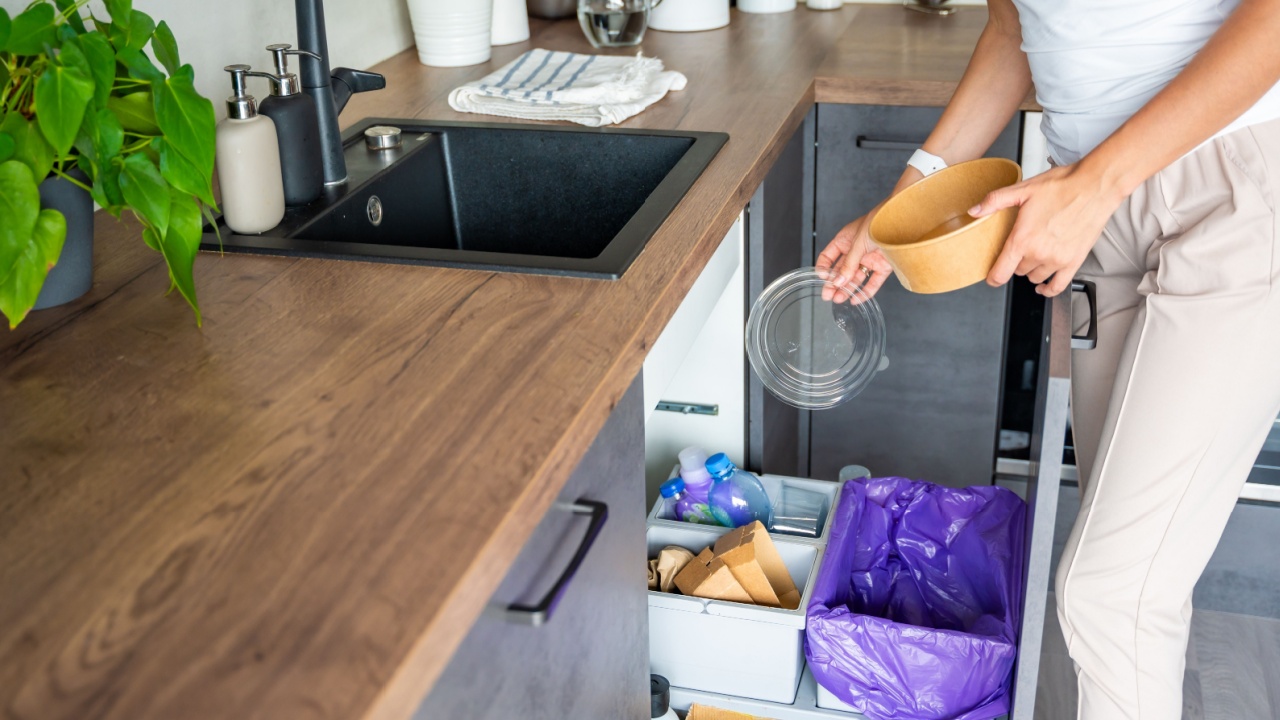 Woman throwing trash into household bins for waste sorting in the kitchen for recycle. Plastic, paper, bio and mixed waste. Sorting waste at home concept. High quality photo