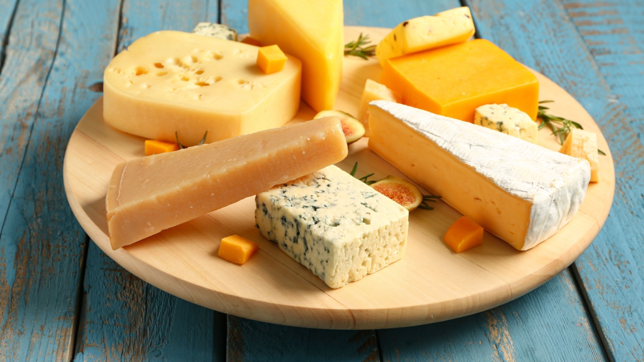 Board with tasty cheese on blue wooden background
