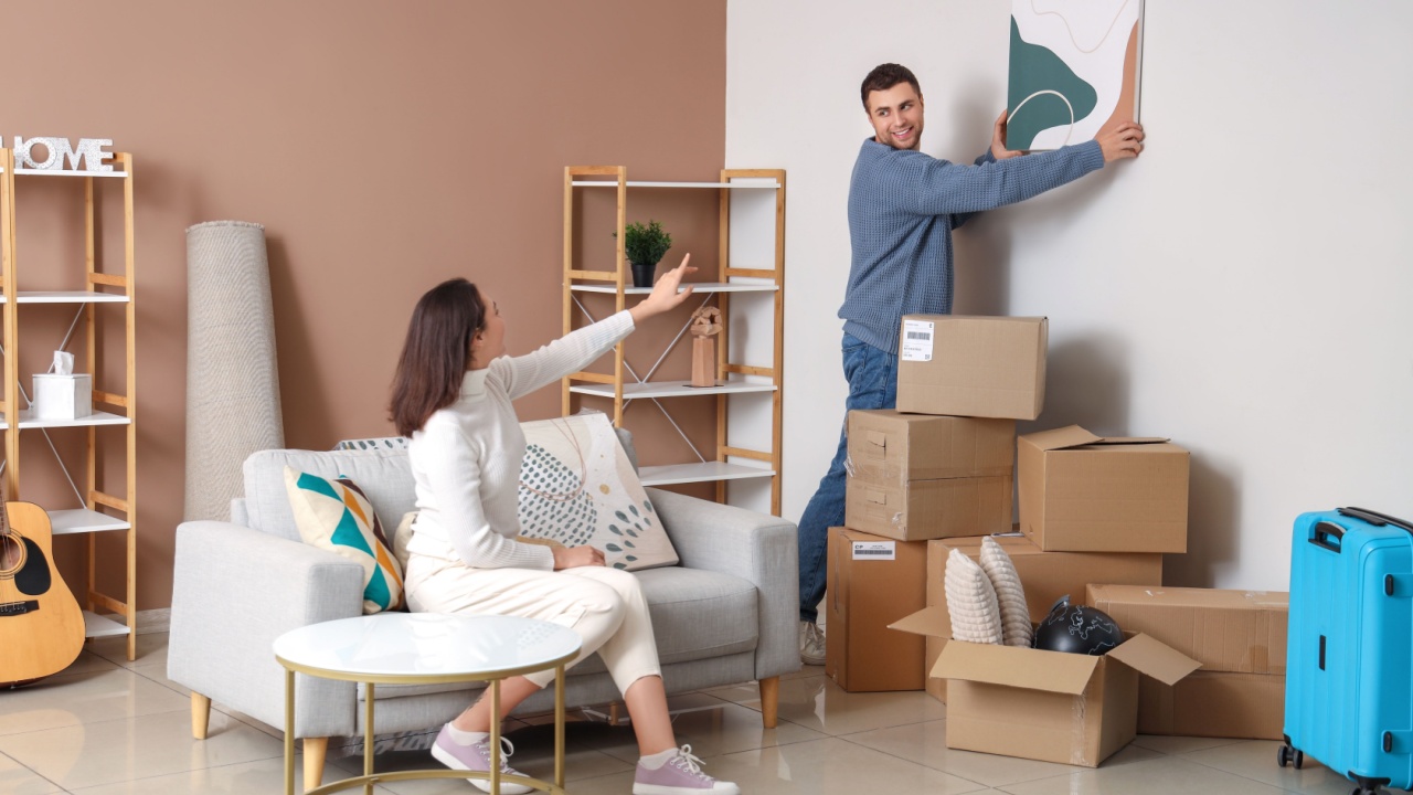 Happy young couple with painting in room on moving day