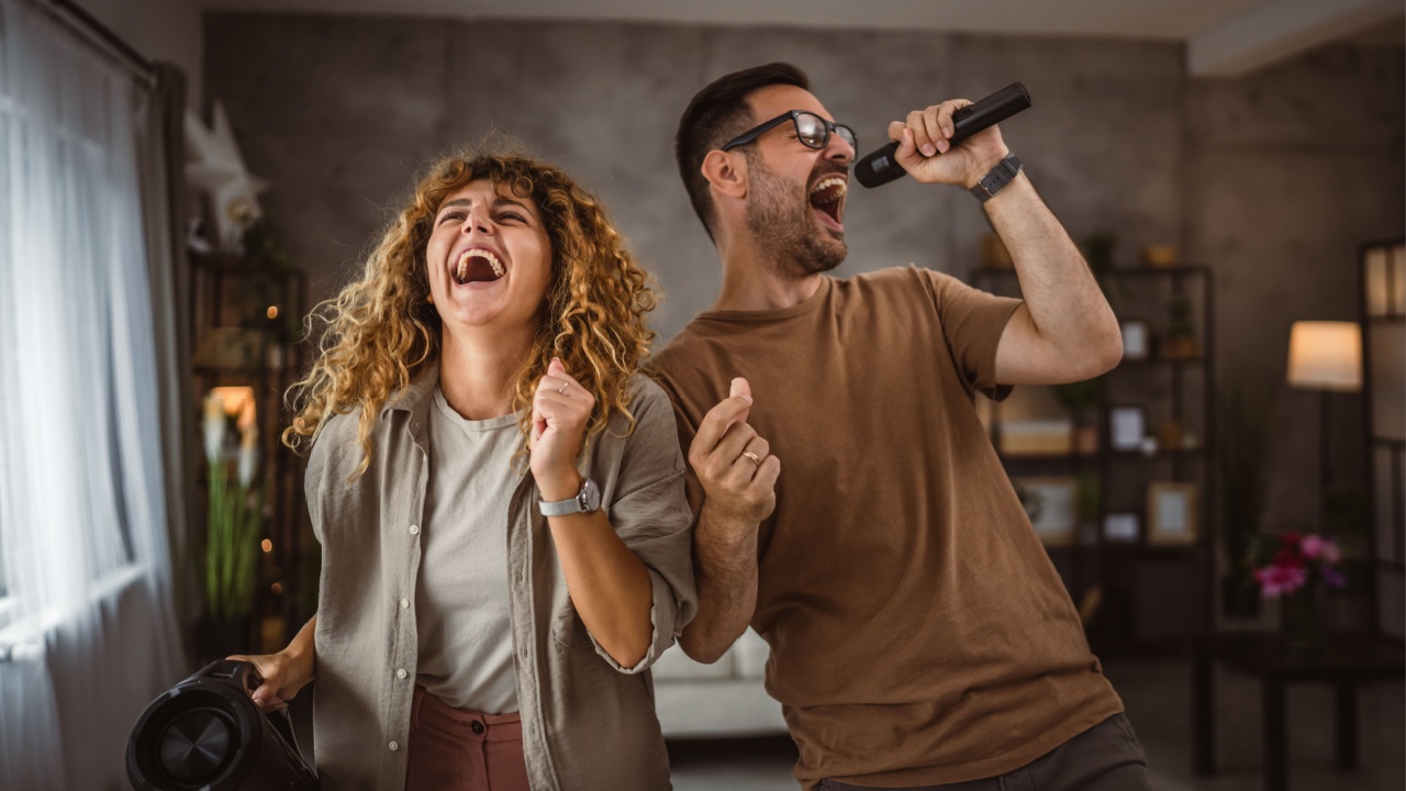 Boyfriend sing on microphone while girlfriend hold loudspeaker karaoke
