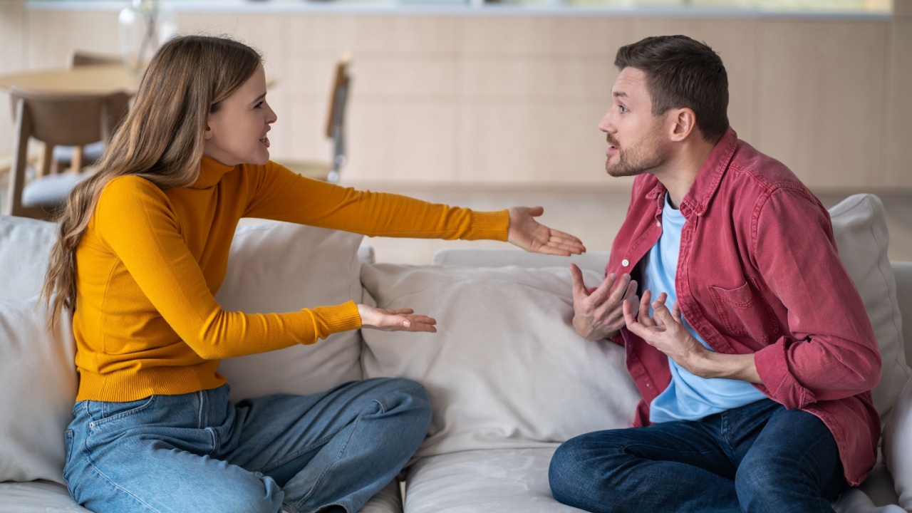 Married couple spouses quarrel, squabbling, fighting, vigorously gesticulating while sitting on couch. Aggressive wife blaming husband making excuses. Guy and girl violently discussing acute issue.