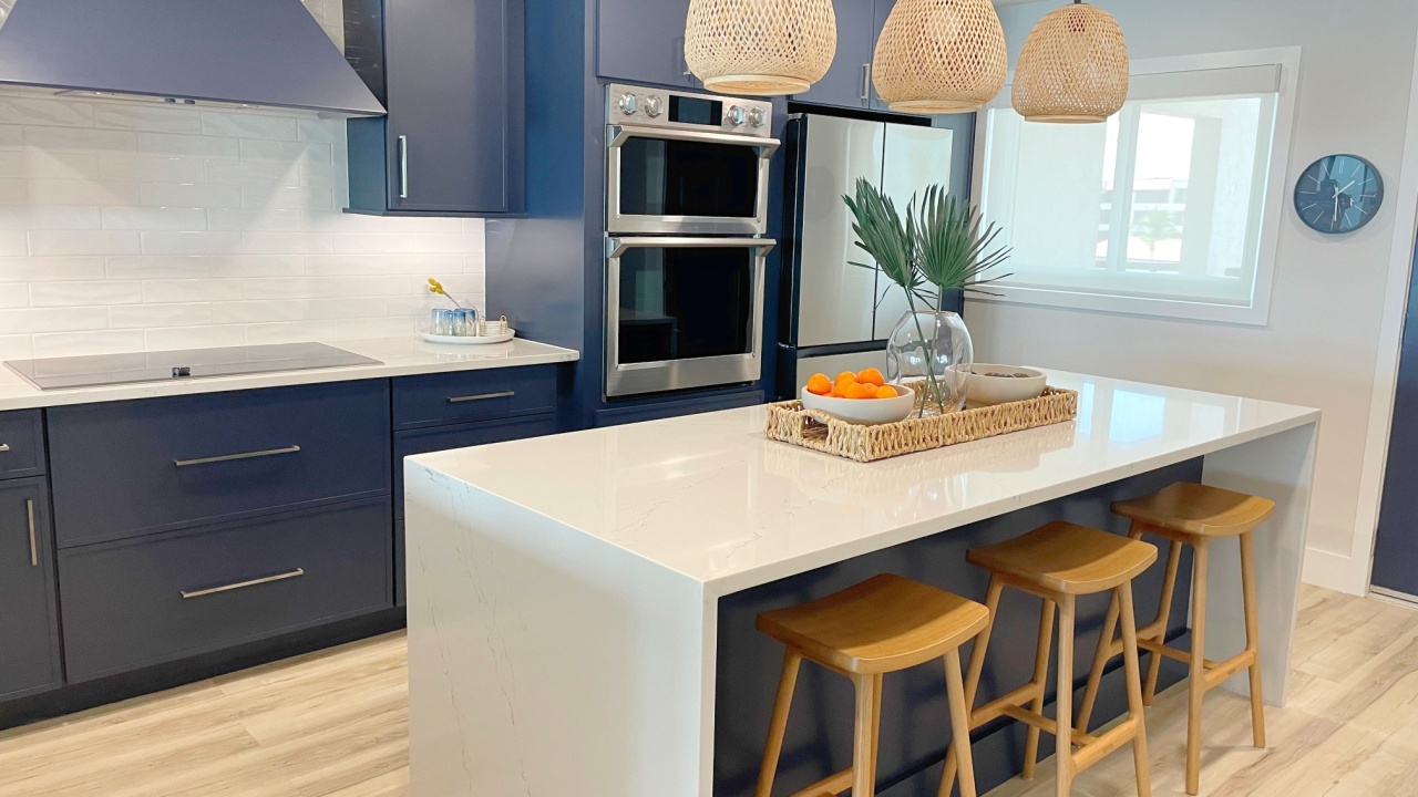 Furnished modern coastal kitchen with blue cabinets, wood floored and white countertops in a beachy setting.