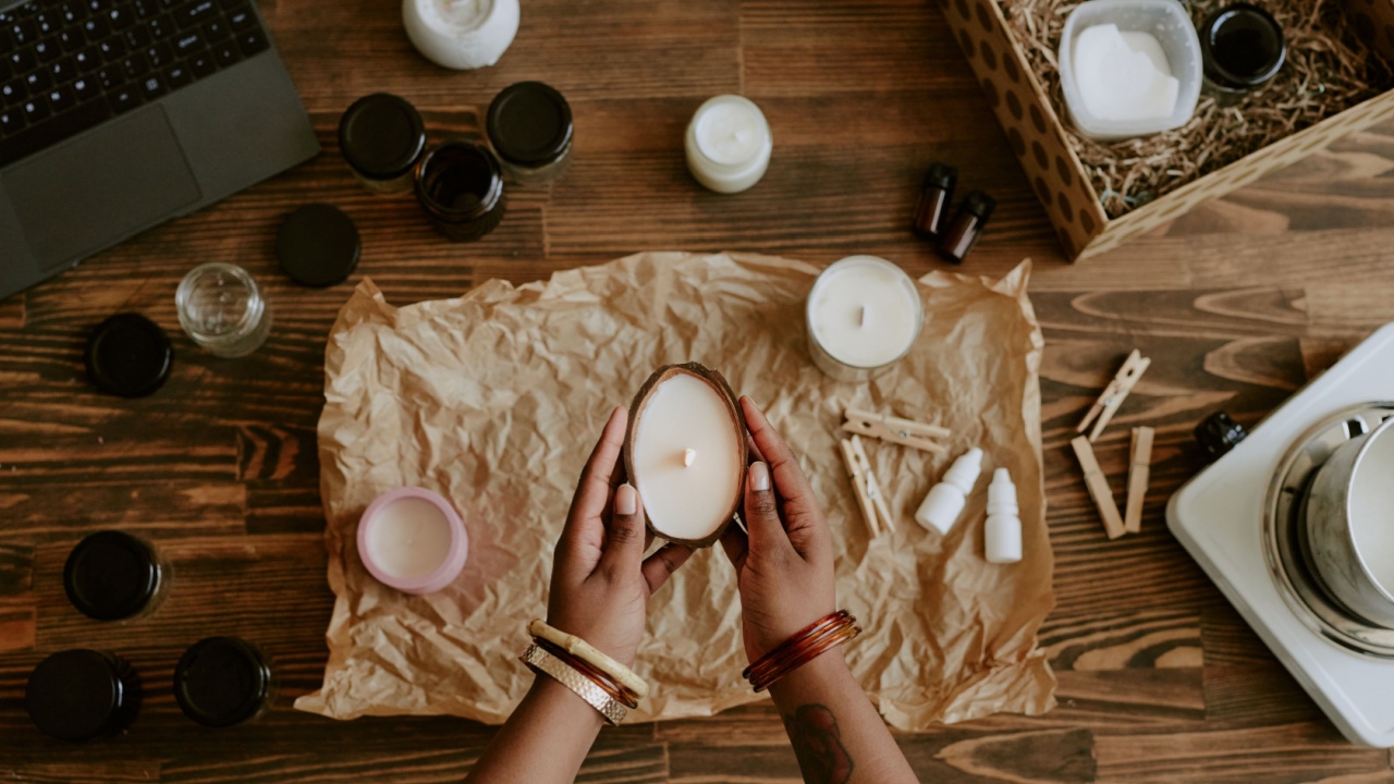 Womans hands are carefully pouring wax into a candle mold onwooden table surrounded by various candle-making supplies and essential oils creating a handcrafted candle