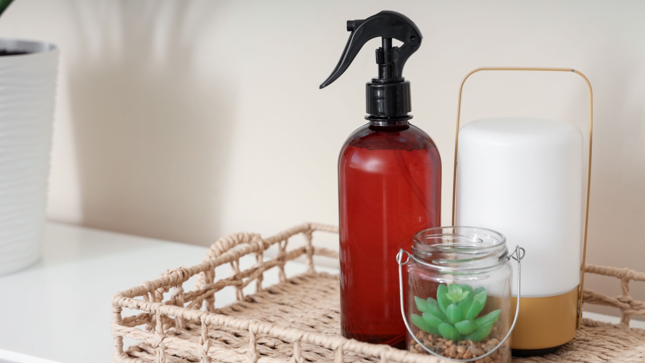 Tray with aroma spray, plant and lamp on shelf in room, closeup