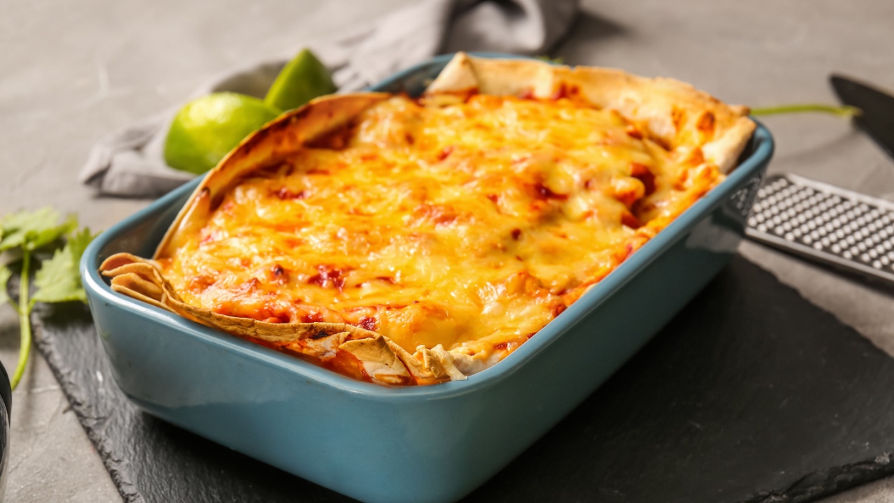 Baking dish with tasty enchilada on table