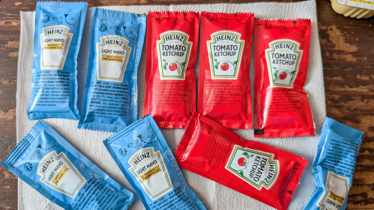 France, 18 August 2024: Assorted packets of Heinz Tomato Ketchup and Light Mayonnaise on a wooden table