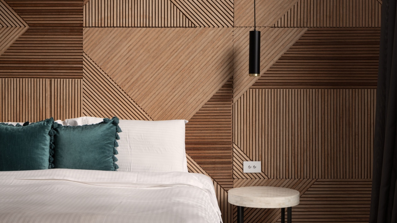 Bed with pillows and geometric timber and wood pattern wall and hanging light. Close up of beautiful abstract wall interior design luxurious bedroom. Filled with natural light. Wood accent wall.