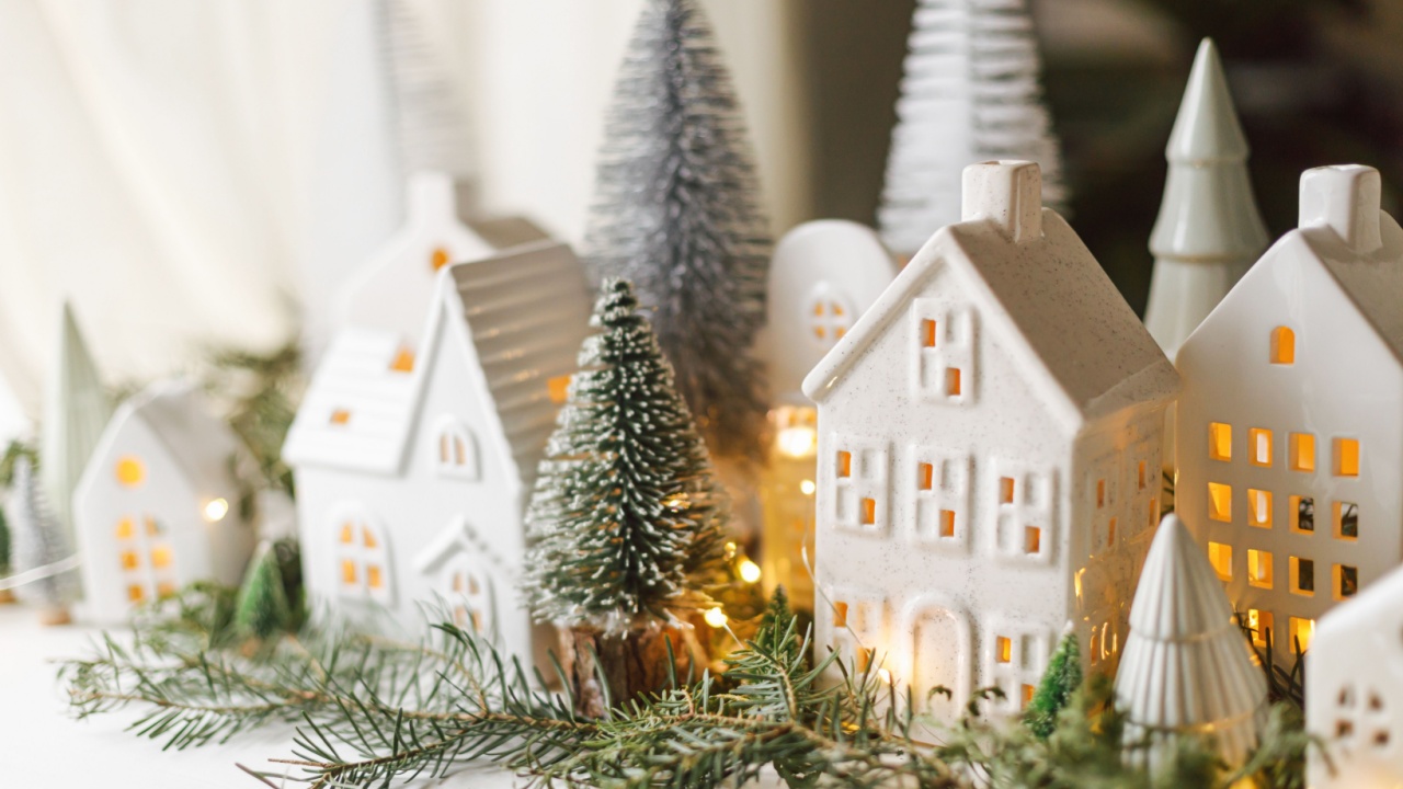 Christmas little ceramic houses, snowy trees and golden lights on dark background in eve. Merry Christmas! Atmospheric Christmas scene, miniature holiday village. Xmas background