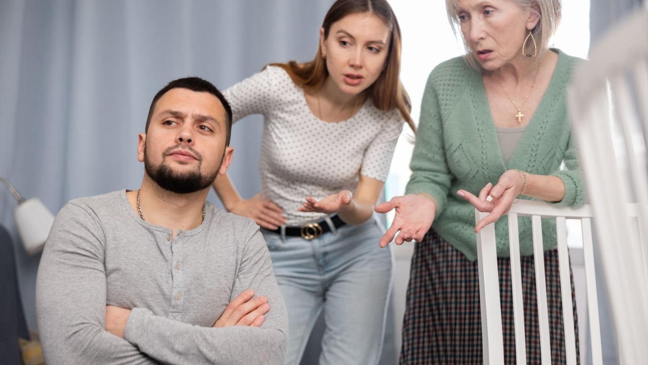 Bored man sitting at home while young and mature female relatives scolding him