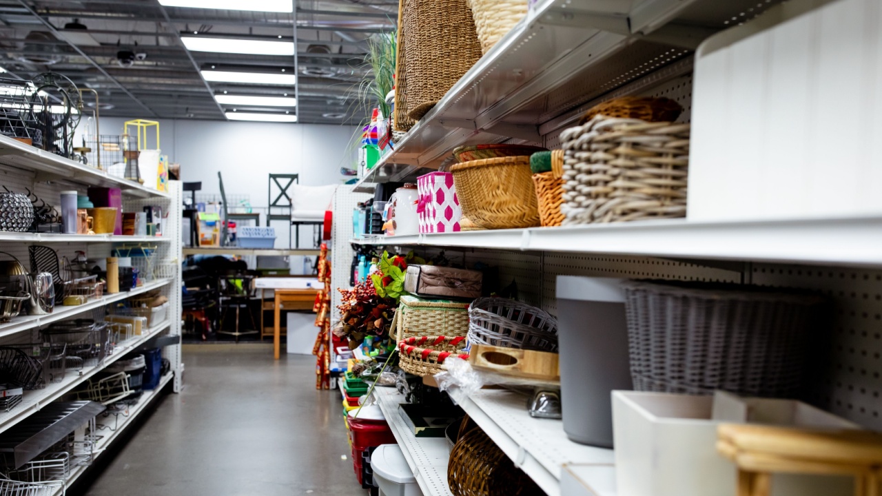 assorted donated second hand household items, arranged on shelves on display in a thrift store. Thrifting