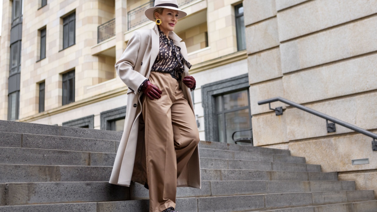Stylish Woman Wearing Fashionable Clothing Beige Coat and trousers, Felt Hat and Accessories Walking Against of Urban Buildings in City, Street Style and Fashion Trends, Winter or Autumn Outfit