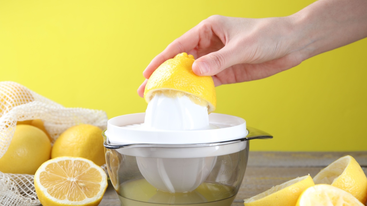 Woman with lemon using juicer at wooden table, closeup