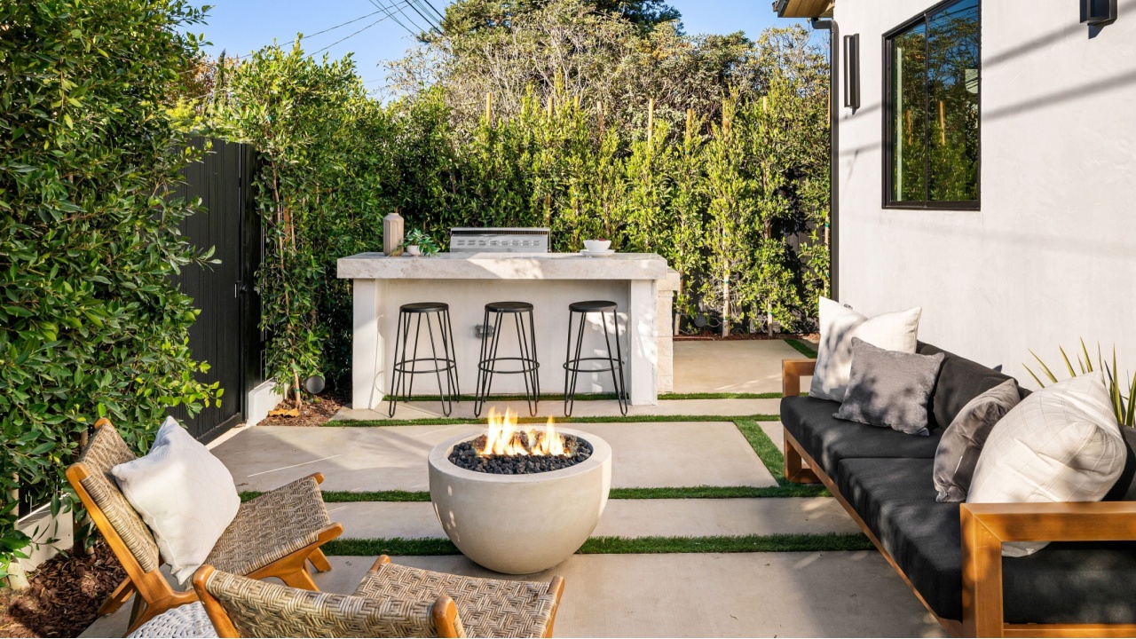 Modern outdoor patio with fire pit, seating, and greenery, perfect for relaxation and gatherings.