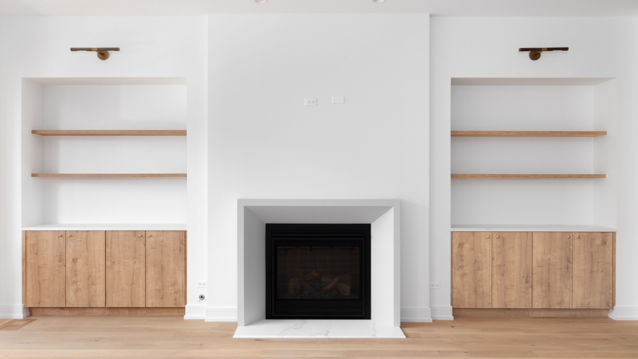 A fireplace detail with built-in white oak shelving and flooring, black lights mounted above the shelves, and white trim around the fireplace.